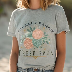 May include: A gray t-shirt with a graphic design of yarn balls and leaves. The text "Yarnley Farms Fresh Spun" is printed on the shirt.