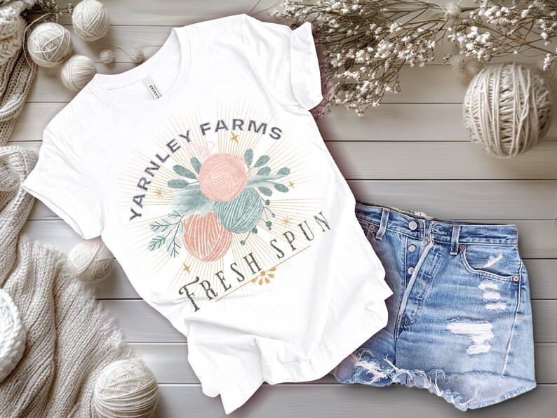 May include: White t-shirt with a graphic design of yarn balls and the text "Yarnley Farms Fresh Spun".