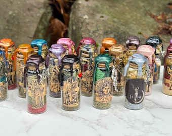 May include: A collection of small glass bottles with colorful wax seals and labels featuring Greek mythology figures. The bottles are filled with dried herbs and spices. The seals are in various colors, including orange, blue, pink, and green.