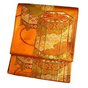 Op de afbeelding: Gevouwen oranje stof met een gedetailleerd patroon. Het ontwerp omvat geometrische vormen, een grote zeshoekige doos met een strik en golfachtige patronen. Gouden en groene accenten versterken de algehele esthetiek. De stof lijkt zijde of een vergelijkbaar materiaal te zijn.