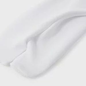 May include: Close-up of the bottom of a white pair of sweatpants. The sweatpants have a seam down the center of the back.