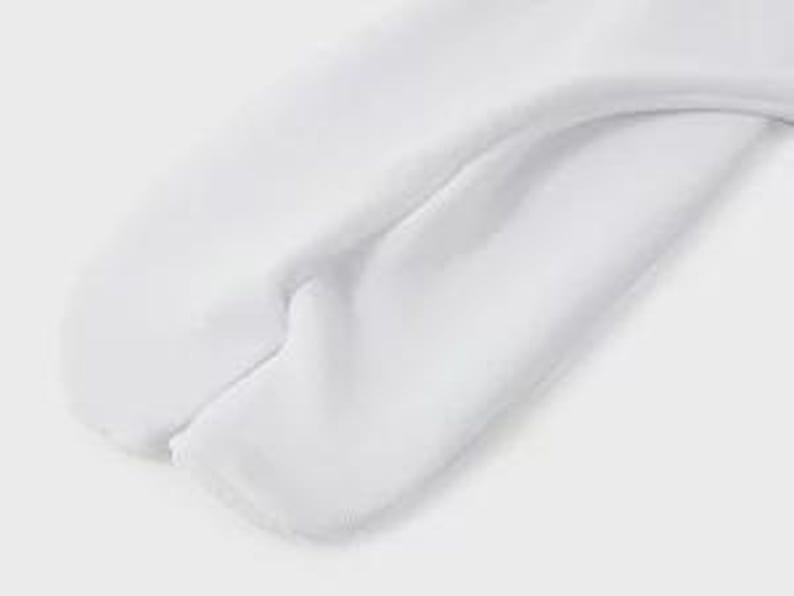 May include: Close-up of the bottom of a white pair of sweatpants. The sweatpants have a seam down the center of the back.