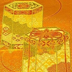 Op de afbeelding: Twee sierlijke, zeshoekige dozen met ingewikkelde patronen en gouden accenten. De dozen hebben rode en groene details en staan tegen een goudkleurige achtergrond met patronen. De dozen lijken decoratief te zijn of voor opslag.