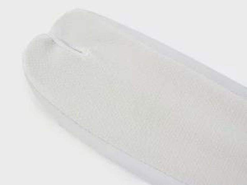 May include: White tabi socks with a split toe design. The socks are made of a soft, breathable fabric.