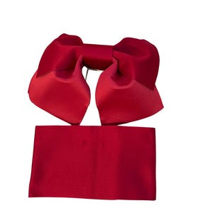 May include: A deep red satin hair accessory consisting of a large, structured bow with two wide, folded loops and a separate, rectangular fabric band positioned directly below the bow, both featuring a smooth, reflective, and uniform finish.