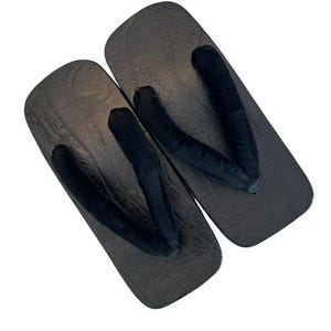 May include: A pair of traditional Japanese geta sandals featuring rectangular dark brown wooden bases with a visible wood grain texture and thick, soft black fabric thong straps positioned in a V-shape across the top of each sandal.