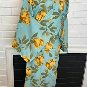 May include: A light blue kimono featuring a repeating pattern of golden yellow tulip-like flowers and muted green leaves. The garment has wide sleeves, a wrap-front closure, and a structured collar, displayed on a mannequin torso.