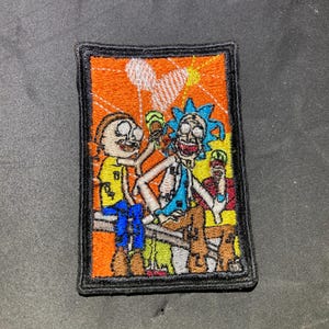 Puede incluir: Parche bordado con los personajes de dibujos animados Rick y Morty, sobre un fondo naranja. El parche tiene un borde negro y representa a los personajes sosteniendo bebidas. Los personajes llevan ropa amarilla y azul.