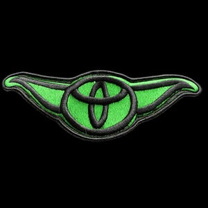 May include: Embroidered patch featuring the Toyota logo in black, set against a vibrant green background. The design is shaped like a stylized wing, with the Toyota emblem at the center. The patch is on a black background.
