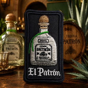 May include: A rectangular black embroidered patch featuring a white tequila bottle with a tan cork and a green thread accent. The bottle label displays the text PATRON, and the word El Patrón is stitched in white lettering at the bottom.