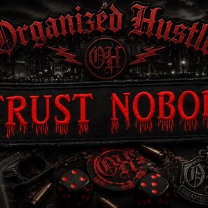 May include: A rectangular black patch featuring the red embroidered text TRUST NOBODY with a dripping effect. Above the text, the words Organized Hustle and the letters OH are displayed in red. The design includes a Las Vegas sign and dice.