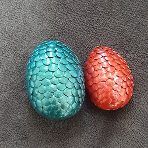 May include: Two dragon eggs, one teal blue and one red, with a scaly texture.