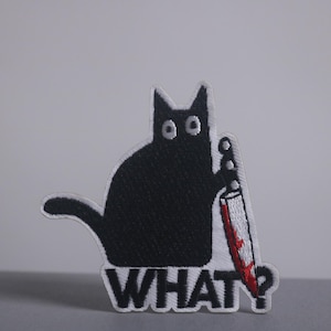 May include: Embroidered patch featuring a black cat holding a knife with a red blade. The cat has wide eyes and the word "WHAT?" is embroidered below. A humorous and edgy accessory.