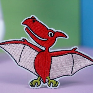 May include: Red embroidered iron-on patch of a cartoon pterodactyl with pink wings.