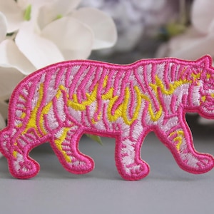 Può includere: Toppa da stirare ricamata rosa e gialla con un tigre. La tigre sta camminando e ha un motivo a strisce.