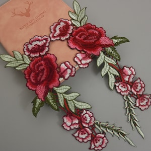 Peut inclure: Deux appliques florales brodées avec des fleurs rouges et blanches et des feuilles vertes. Les appliques sont parfaites pour ajouter une touche d'élégance aux vêtements, aux sacs ou aux projets de décoration intérieure.