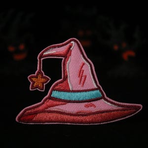 May include: A pink and red embroidered witch hat with a blue band and a star on the brim.