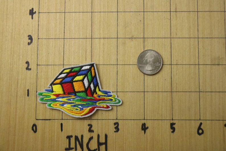 May include: A colorful embroidered iron-on patch of a melting Rubik's Cube. The patch is about 2 inches wide and 2 inches tall.