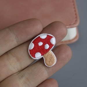 Op de afbeelding: Een geborduurde rode en witte paddenstoel patch met witte stippen. De paddenstoel heeft een bruine steel.