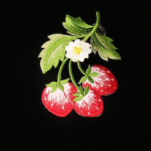Könnte beinhalten: Gestickter Aufnäher mit drei roten Erdbeeren mit grünen Blättern und einer weißen Blüte.