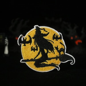 Peut inclure: Un patch brodé représentant une silhouette de sorcière noire chevauchant un balai devant une lune jaune avec des chauves-souris qui volent autour.