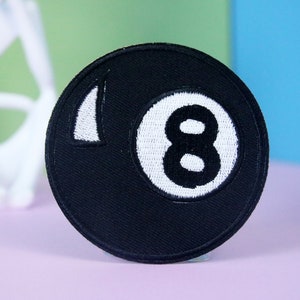 Op de afbeelding: Zwart-witte geborduurde patch van een biljartbal met het nummer 8 erop.