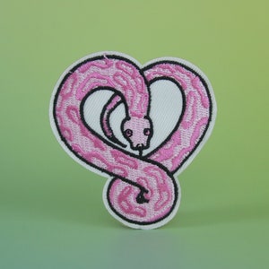 Può includere: Toppa da stiro ricamata rosa a forma di cuore con un serpente.