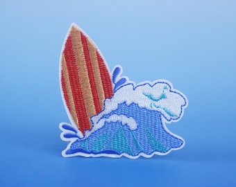 May include: A red and brown surfboard with white stripes is partially submerged in a blue and white wave. The wave is breaking and has a white foamy crest.