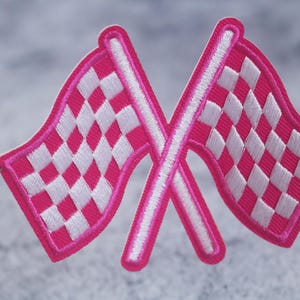 May include: Two pink checkered racing flags crossed over each other. The flags are white and pink and have a white outline.