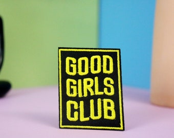 May include: Black iron-on patch with yellow embroidered text that reads "GOOD GIRLS CLUB".