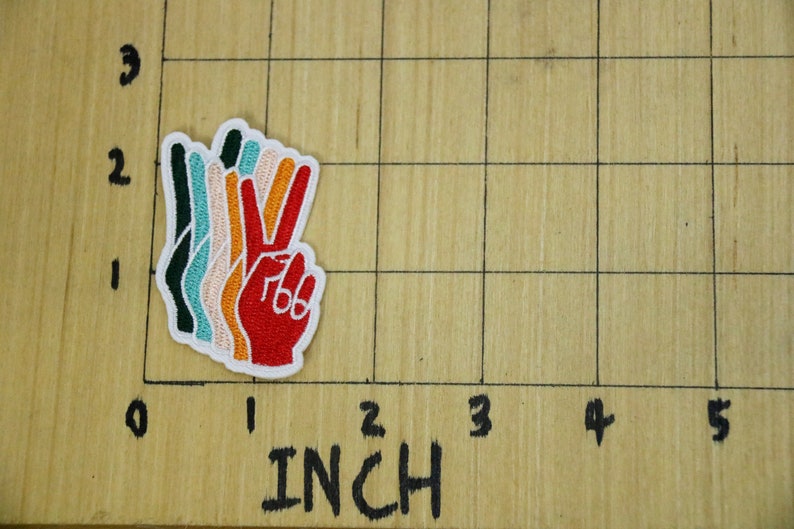 Pu&ograve; includere: Toppa ricamata colorata a forma di simbolo della pace, con una mano rossa con dettagli bianchi e un bordo bianco. La toppa &egrave; stratificata con colori verde, turchese, pesca e arancione. La toppa misura circa 5 cm di altezza.