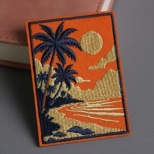 May include: Embroidered patch depicting a tropical sunset. The design features navy blue palm trees, a golden sun, and a river against an orange backdrop. The patch has a navy blue border.