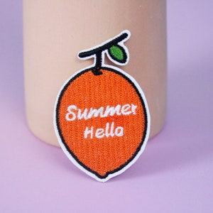 May include: Orange embroidered iron-on patch with the text "Summer Hello" in white thread.