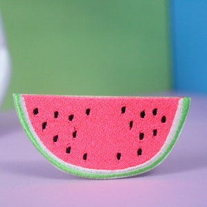 May include: Embroidered watermelon patch. The patch features a bright pink watermelon slice with black seeds and a green rind. The patch is a fun accessory for clothing or bags.