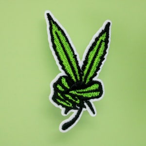 May include: Green embroidered patch of a marijuana leaf in the shape of a peace sign.