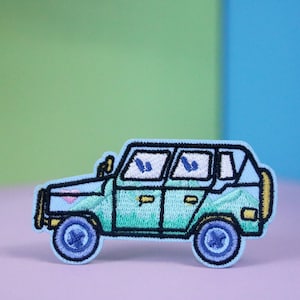 Könnte beinhalten: Ein gestickter Aufnäher, der einen Cartoon-Jeep in Blau und Grün mit gelbem Stoßfänger und schwarzen Rädern zeigt.