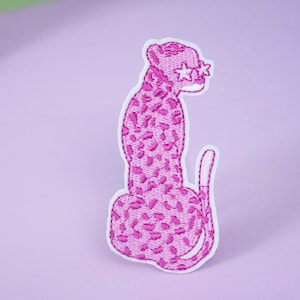 Könnte beinhalten: Rosa gestickter Bügel-Patch mit einem Leoparden, der sternförmige Sonnenbrillen trägt.