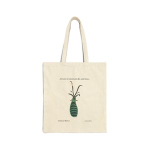 Op de afbeelding: Een beige tote bag met een illustratie van een groene en zwarte kever. De tekst "A Study of Creatures Big and Small" en "Stardust Beetle" staat op de tas gedrukt.