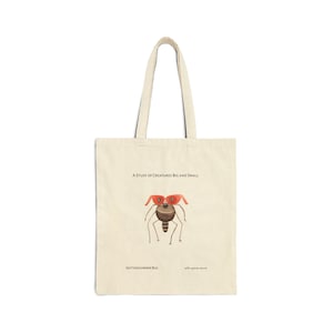 Op de afbeelding: Een beige tote bag met een illustratie van een bruin en rood insect. De tekst "A Study of Creatures Big and Small" is boven het insect gedrukt. De tekst "Skitter-shimmer Bug" is onder het insect gedruckt.