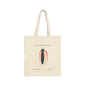 Op de afbeelding: Een beige tote bag met een zwarte en rode illustratie van een kever op de voorkant. De tekst "A Study of Creatures Big and Small" is boven de kever gedrukt en "Starlight Beetle" is onder de kever gedrukt.