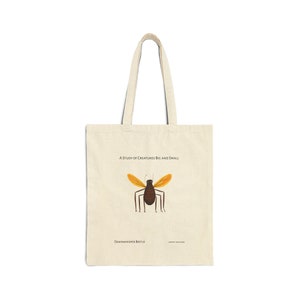 Op de afbeelding: Een beige tote bag met een illustratie van een bruin en geel insect. De tekst "A Study of Creatures Big and Small" staat boven het insect gedrukt en "Dawnwhisper Beetle" staat onder het insect.
