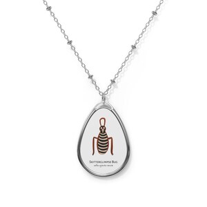 May include: A silver chain necklace with a silver oval pendant featuring a cartoon illustration of a brown and black striped bug with the text "SKITTERGLIMPSE BUG" and "salix agrifolia amate"