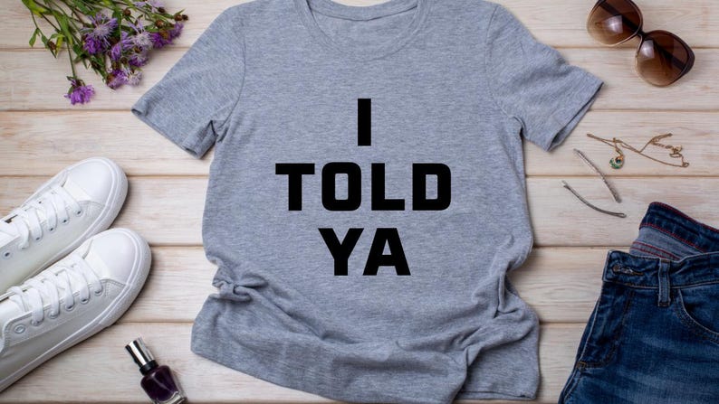 May include: A gray t-shirt with the text "I TOLD YA" printed in black.