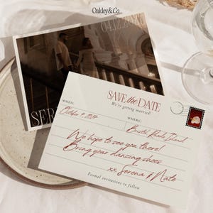 May include: A rectangular Save the Date postcard featuring a photograph of a couple on a staircase and a cream-colored card with red script text. The card includes the text Oakley&Co., 04.12.2027, SAVE the DATE, October 4, 2027, Bristol, Rhode Island, and Serena & Nate.