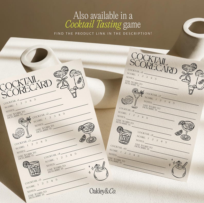 May include: Two off-white paper cocktail scorecards featuring black line art illustrations of various drinks and garnishes. Each card includes sections for cocktail names, numerical scores from 1 to 5, notes, and a space for one descriptive word.
