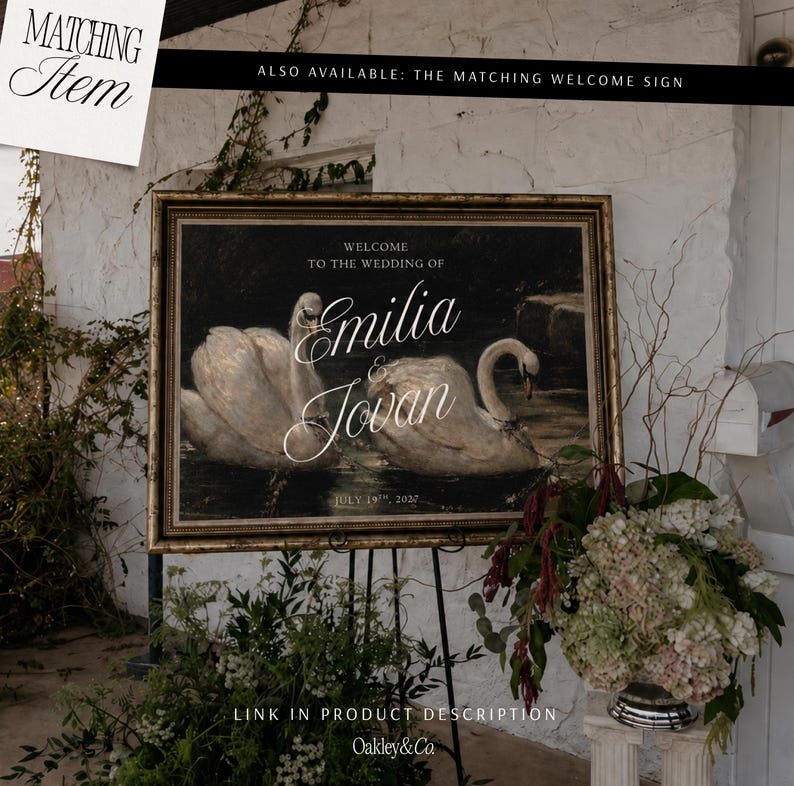 May include: A rectangular wedding sign in a gold ornate frame featuring two white swans on dark water. The text reads: WELCOME TO THE WEDDING OF EMILIA & JOVAN JULY 19TH, 2027. The sign is displayed on a black metal easel stand with floral arrangements.