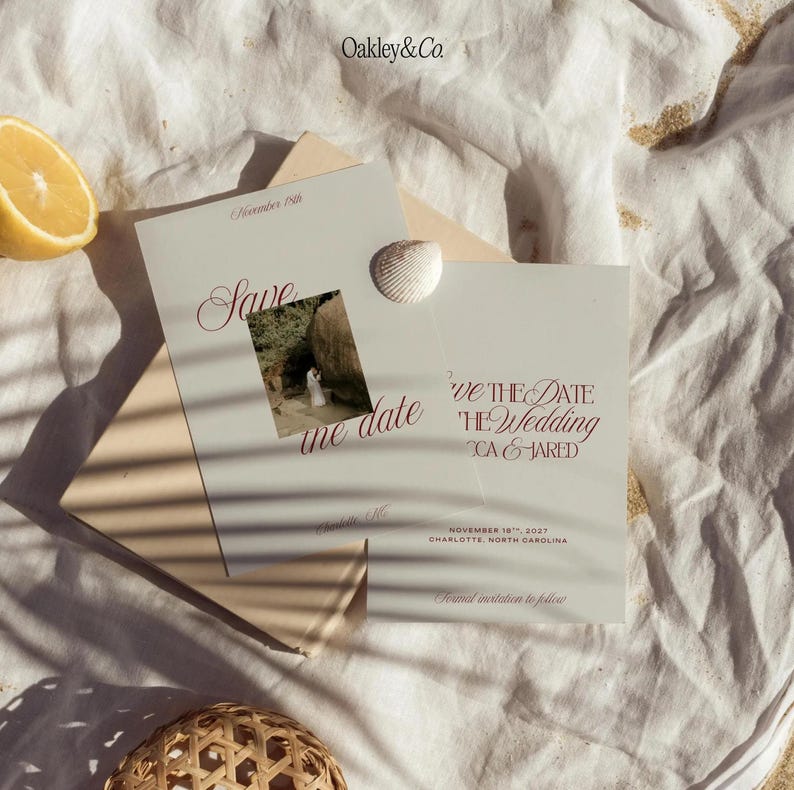 May include: Two off-white Save the Date cards with dark red serif typography and a small square photograph of a couple. The cards feature the text Oakley&Co., Save the date, November 18th, 2027, Charlotte, North Carolina, and Formal invitation to follow.