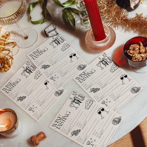 May include: A set of four cream-colored wine tasting cards featuring black line art illustrations of wine bottles, glasses, grapes, and cheese. Each card includes the text WINE TASTING and provides structured lines for scoring and notes.