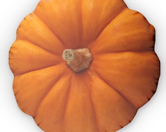 May include: Overhead view of a round, orange pumpkin with a textured surface. The pumpkin has a brown stem and is set against a white background. The pumpkin's shape is defined by vertical ridges.