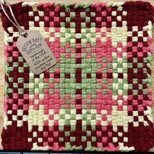 May include: A red, green, pink, and yellow woven pot holder with a brown tag that reads "KRISTIN KAY'S welle LOOPSON & LOOM handwoven in the USA 100% cotton machine wash dry flat"